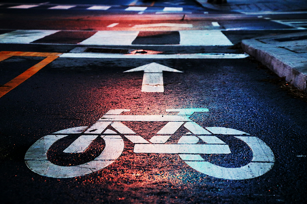 cycling lane A wet road with a white icon of a bicycle and an arrow before a pedestrian crossing