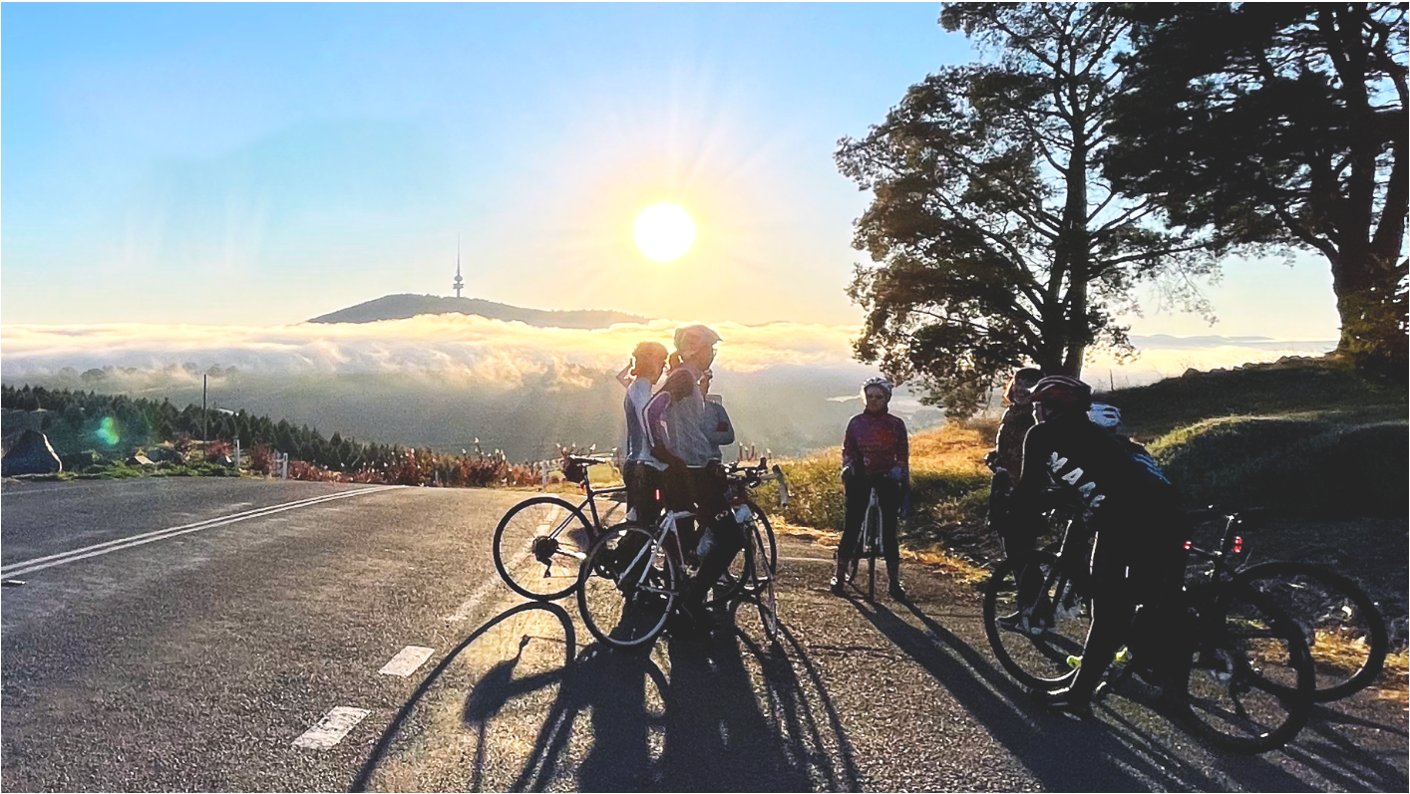 dev-squad A small group of cyclists standing at the side of the road with a sunrise in the background