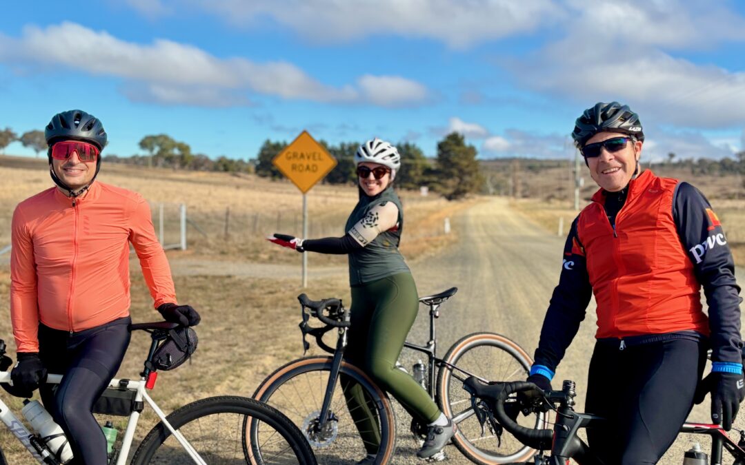 Three cyclists preparing to ride a gravel road, smiling and ready for an adventure