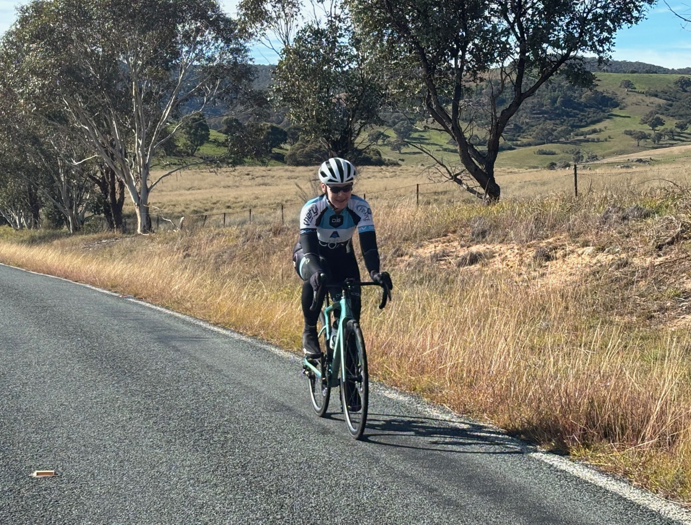A small group of cyclists standing at the side of the road with a sunrise in the background