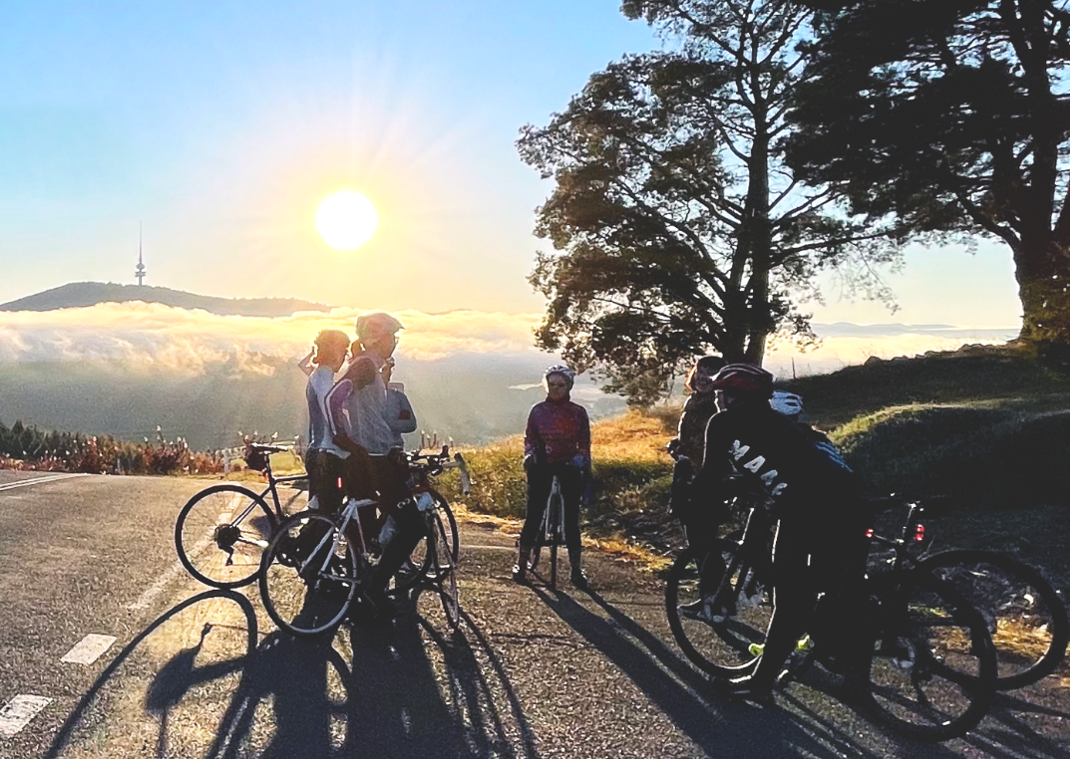 Group of adult cyclists taking a break during a sunrise ride overlooking Canberra